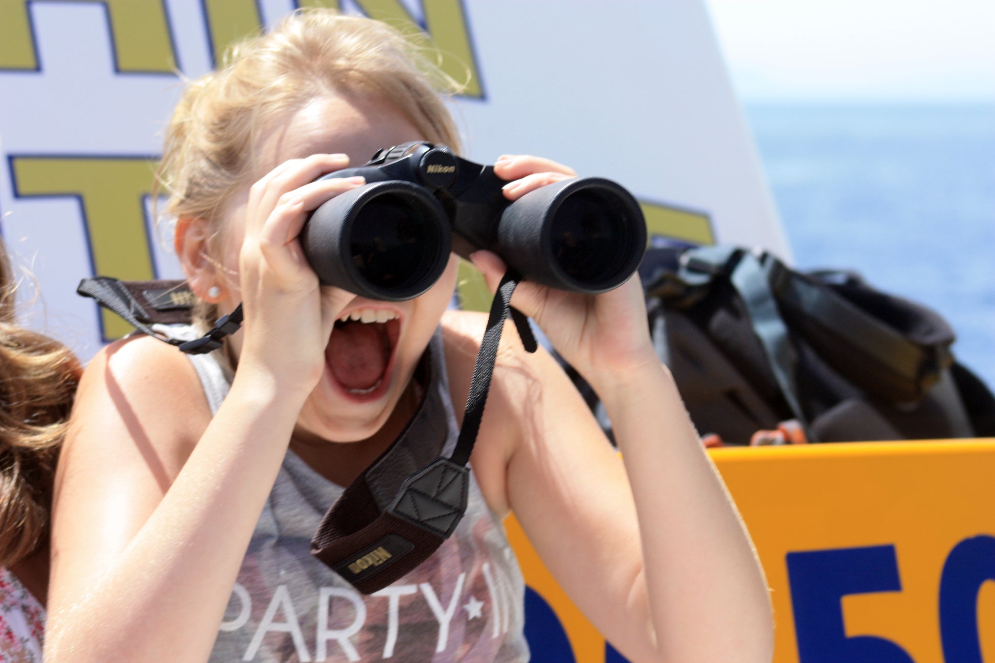 Child watching wild dolphins through binoculars on a Gibraltar boat tour