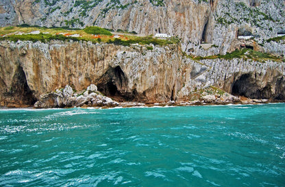 Turquoise waters near Gibraltar rocky cliffs with greenery