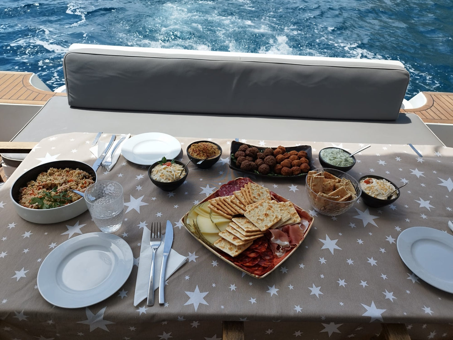 Table set with food and tableware on a yacht with water in the background