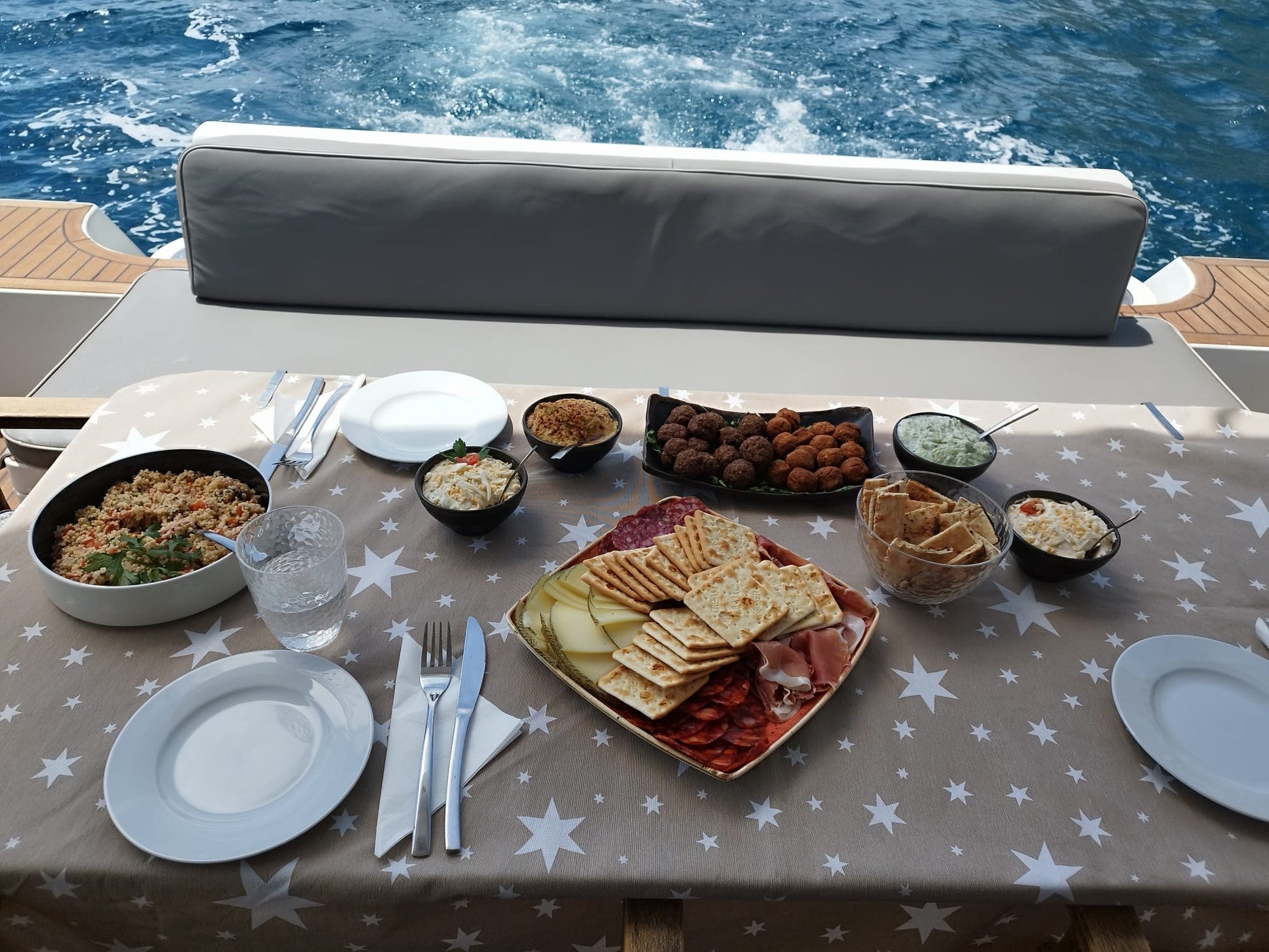 Table set with food and tableware on a yacht with water in the background