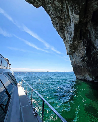 Boat near a rocky cliff in Gibraltar with clear blue sky and water.